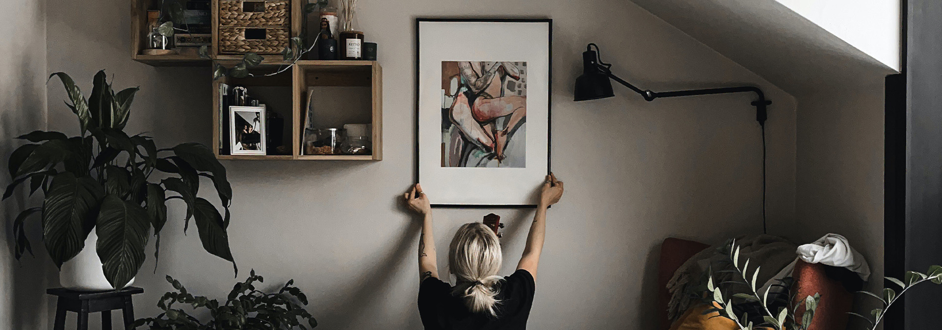 girl hanging picture on the wall